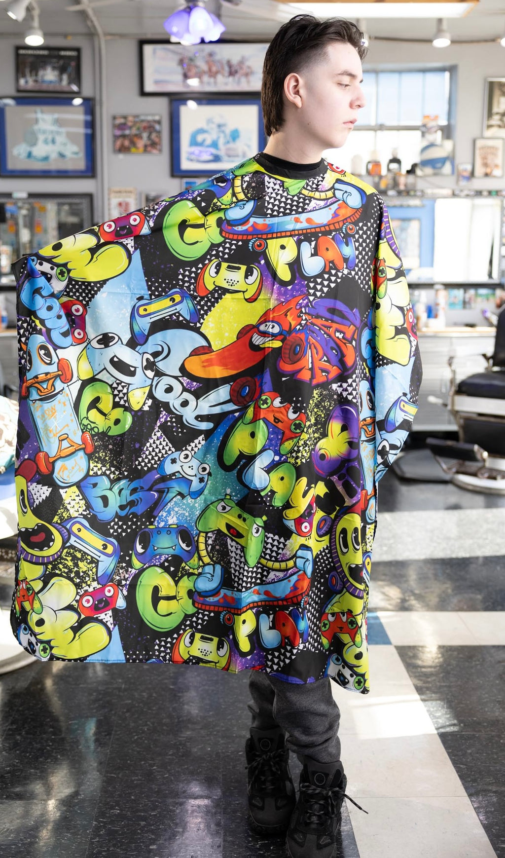 Graffiti Themed waterproof professional barber and salon cape with metal snap closures and unique design including the vibrant colorful style featuring graffiti style gaming controllers skateboards and words play and cool